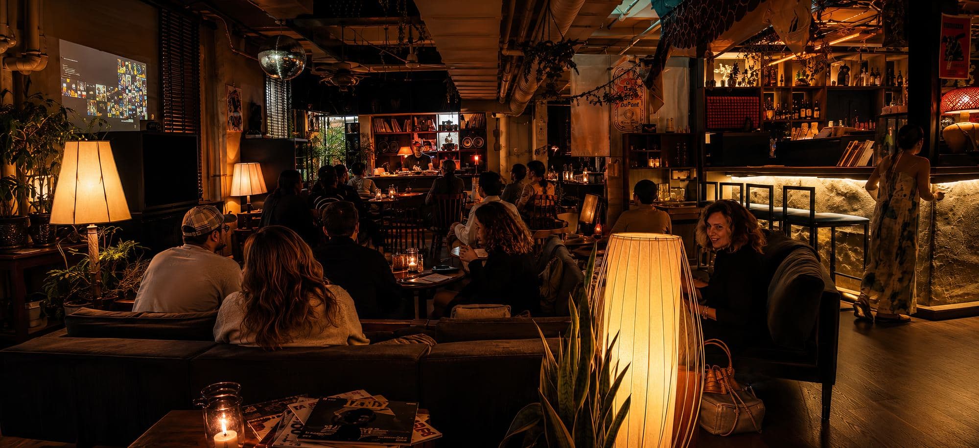The room at 915 Dupont full during a Kiku Listening Session, candlelit tables facing the booth