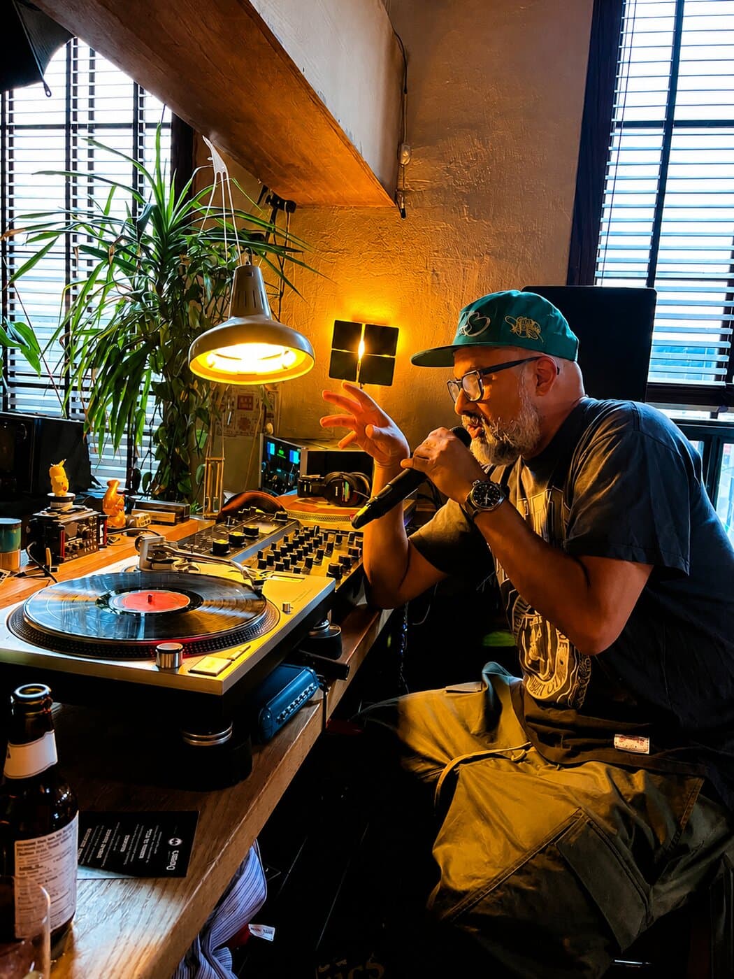 Steven Fernandez hosting a Kiku Listening Session, mic in hand behind the turntables
